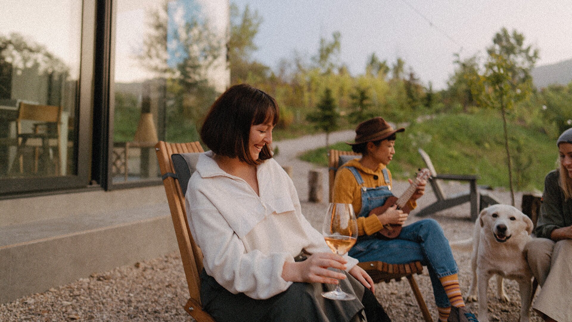 Friends sit outside of their modern home in the mountains enjoying music and wine - new homes at Big Sky Quarry