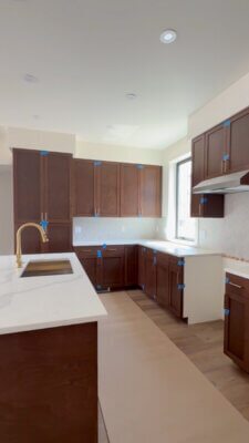 Kitchen in a new Big Sky Quarry home featuring dark wood cabinetry, light countertops, a large island, and a light-filled window.
